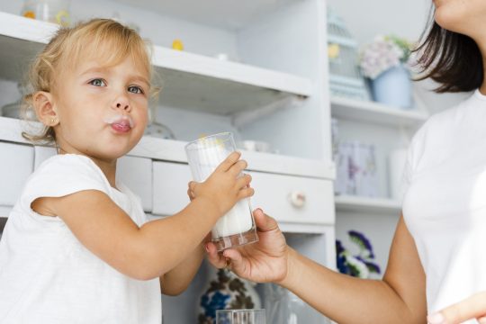 Un bébé qui boit du lait, un produit laitier.